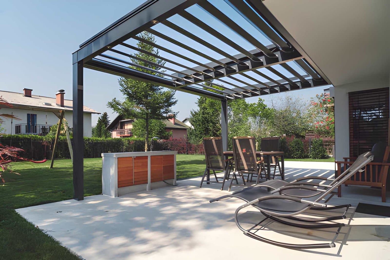 Modern concrete patio with a pergola and lounge seating in a Greeley backyard